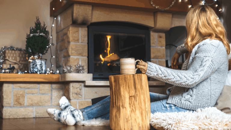 Frau sitzt vor einem Kamin in der Adventszeit