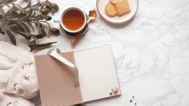 Schönes Notizbuch, Tee und Kuschelschuhe als Deko zum Thema Journaling